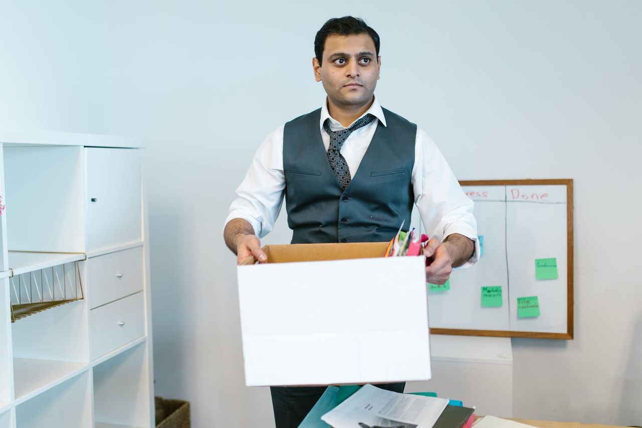Mann räumt Büromaterial in einen Umzugskarton