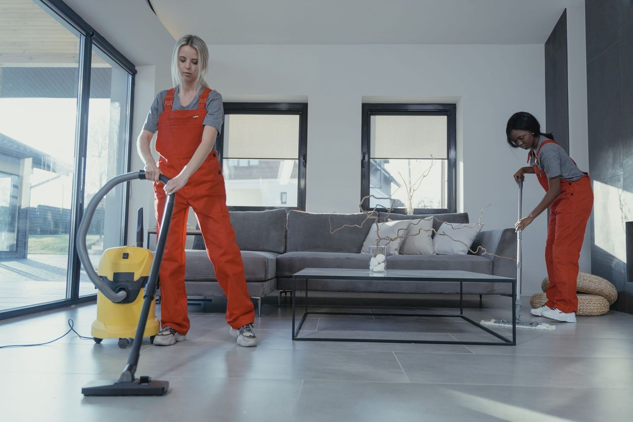 Reinigungskräfte in Arbeitskleidung reinigen einen hellen Wohnraum